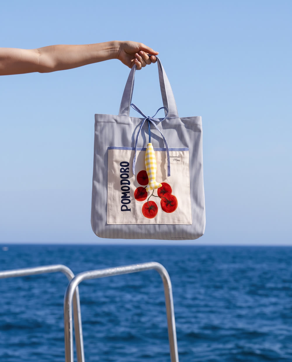 Uma mão segurando O Pomodoro sobre o mar