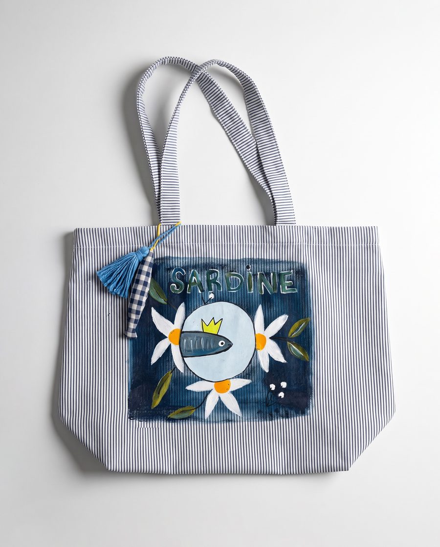 Bolsa A Rainha: sardinha de coroa amarela entre margaridas, pintada sobre riscado de algodão, com borla azul na alça